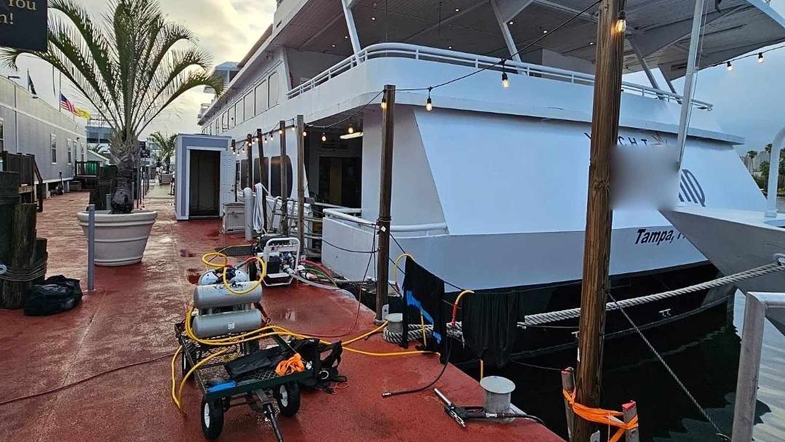 BarnacleBeGone LLC dive gear staged on a Tampa dock alongside a large yacht before an in-water hull cleaning